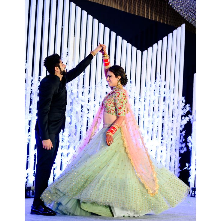 A playful pose where the bride twirls in her saree, with the groom watching her, capturing the joy and vibrancy of the wedding. 